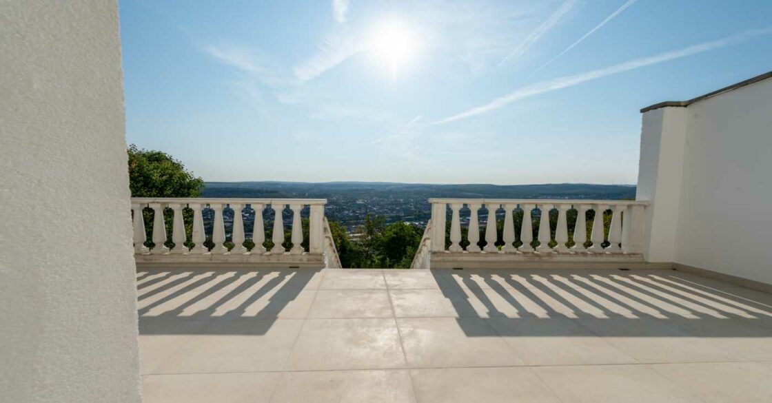 Ausblick bei Sonnenschein von der Terrasse den Hügel herunter.